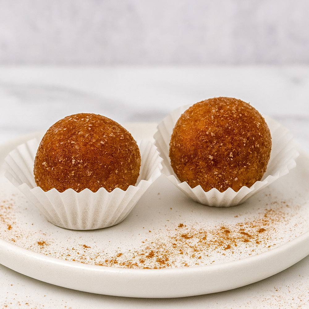 Two brown spherical treats in white paper cups on a white plate with a light gray background Sweetgrub Saint Petersburg 